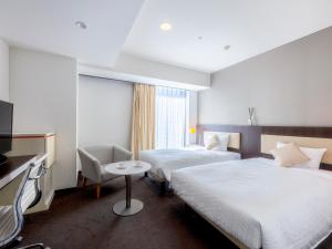 a hotel room with two beds and a television at Hotel Gracery Sapporo in Sapporo