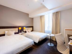 a hotel room with two beds and a window at Hotel Gracery Sapporo in Sapporo