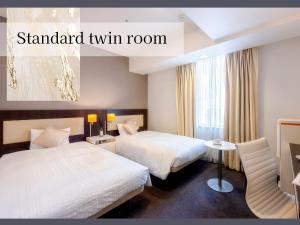 a hotel room with two beds and a window at Hotel Gracery Sapporo in Sapporo