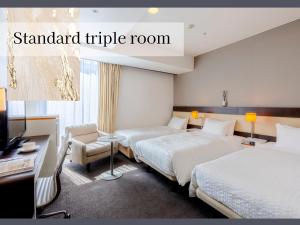 a hotel room with two beds and a desk at Hotel Gracery Sapporo in Sapporo