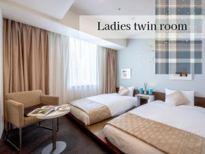 a hotel room with two beds and a chair at Hotel Gracery Sapporo in Sapporo