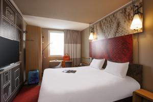 a hotel room with a large white bed and a tv at ibis Paris Porte de Clichy Centre in Clichy