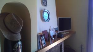 a shelf with a monitor and books and a clock at 1878 Sorrento Guest House in Sorrento