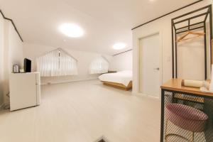 een witte slaapkamer met een bed en een koelkast bij Seorak HOT Spring Mammoth Resotel in Sokcho