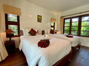 a bedroom with two beds with white sheets and windows at Maikaew Damnoen Resort in Damnoen Saduak +102 photos