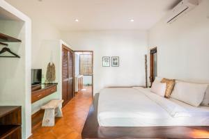 een witte slaapkamer met een bed en een televisie bij Flor Villa by Betterplace in Dalung