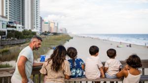 a family sitting on a bench at the beach at Holiday Inn Club Vacations Myrtle Beach Oceanfront in Myrtle Beach