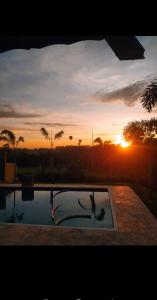 a sunset over a swimming pool with the sun setting at Belíssima Chácara de Alto Padrão em Boituva in Boituva