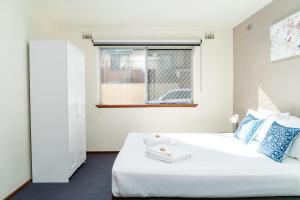 a white bedroom with a bed and a window at Apartment 3 Burswood in Perth