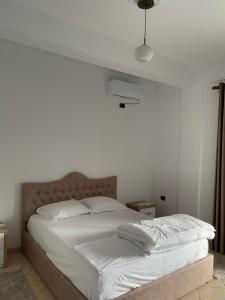 a white bed in a white bedroom with a ceiling at Comfortable and Luxurious home in Kamëz