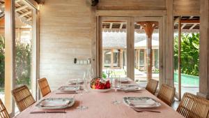un comedor con una mesa larga con platos y copas de vino en Villa Du Ho by Villa Finder, en Kerobokan