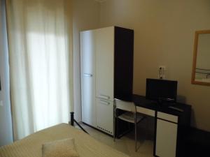 a bedroom with a refrigerator and a desk with a computer at Appartamento Orchidea in Pescara