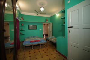 a bedroom with green walls and a bed and a door at Holi-Wood Guesthouse in Puducherry