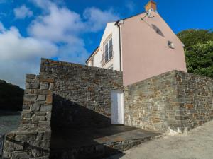 Un edificio detrás de una pared de ladrillos con una puerta blanca. en Curlew, en Milford Haven