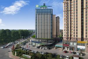 a tall building with a parking lot in a city at Holiday Inn Express Linyi West by IHG in Linyi