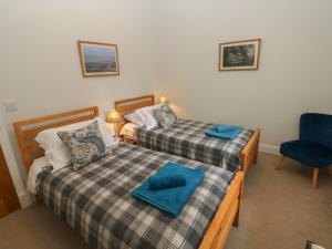 1 dormitorio con 2 camas y silla azul en The Old Carriage Court, en Kidwelly