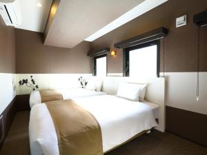 a bedroom with two beds and a window at KOKO HOTEL Ueno Station in Tokyo