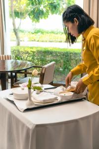 a woman standing at a table with a tray of food at Marasa Sarovar Premiere, Bodhgaya in Bodh Gaya +37 photos
