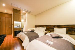 a hotel room with two beds and a television at Coco Hotel in Incheon