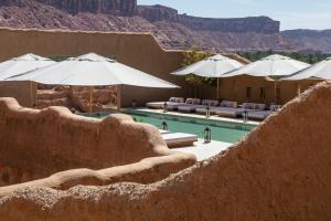 a resort with a pool with umbrellas and mountains at Dar Tantora The House Hotel in Al-ʿUla