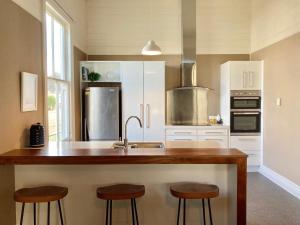 a kitchen with a sink and two bar stools at Riverside Villa in Whanganui