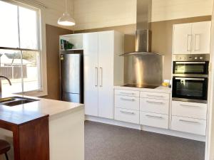 a kitchen with white cabinets and a stainless steel refrigerator at Riverside Villa in Whanganui