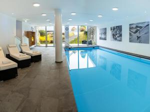 ein großes Schwimmbad in einem Raum mit Stühlen in der Unterkunft Hotel Hanauerlehen - ruhige & zentrale Top-Lage - mit Schwimmbad, Sauna, Parkplätze & Café - bayerischer Familienbetrieb in Schönau am Königssee