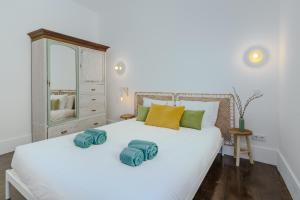 a bedroom with a white bed with green and yellow pillows at Sunny & Charming Oeiras Historical Center House in Oeiras
