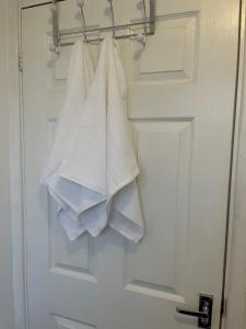 a group of white towels hanging on a door at Kettering Service Accomodation 2BRH FreeParking Wifi Smart TV Tea & coffee in Kettering