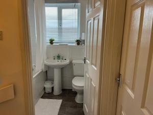 a bathroom with a toilet and a sink and a window at Kettering Service Accomodation 2BRH FreeParking Wifi Smart TV Tea & coffee in Kettering