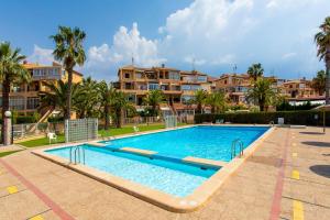 a large swimming pool with palm trees and houses at Perseo in Torrevieja