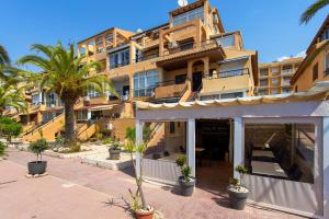 a large building with palm trees in front of it at Perseo in Torrevieja