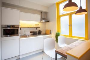 a kitchen with white cabinets and a table and chairs at Higgihaus Aparthotel, Clare Street in Bristol +83 photos