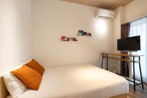 a small bedroom with a bed and a flat screen tv at GROUNDEUX Ohmorimachi in Tokyo
