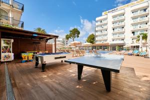 a ping pong table on a patio with a pool at AluaSun Continental Park Hotel & Apartments in Playa de Muro