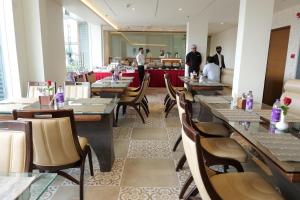 a restaurant with tables and chairs and people in the background at Florida Airport Hotel Kochi in Nedumbassery