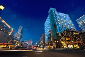 a city street at night with a tall building at Hotel Gracery Sapporo in Sapporo