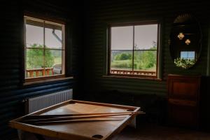 a room with a wooden table in front of two windows at Grava Cottage in Tukums
