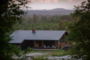 a black house with two chairs and a porch at Grava Cottage in Tukums +31 photos