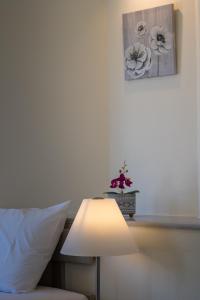 a table with a white lamp next to a bed at Erato Hotel in Agia Marina Aegina