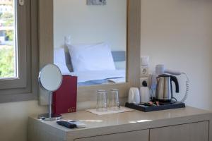 a bathroom with a vanity with a mirror and a bed at Erato Hotel in Agia Marina Aegina