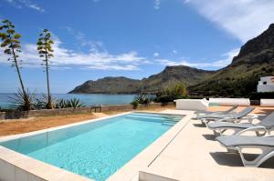 a pool with chairs and the ocean in the background at XOROI- Villa primera linea mar con vistas a Bahía Alcudia in Artá