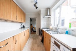 a kitchen with wooden cabinets and a sink and a window at Enjoy a spacious 3 BR home in Sunderland