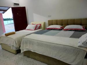 two beds sitting next to each other in a bedroom at Roomstay TokBah DeMuara Kuala Besut in Kuala Besut
