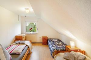 a attic room with two beds and a window at Ferienhaus Lüttje Dörp in Blomberg