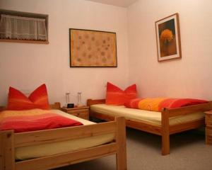 2 Betten mit roten und orangefarbenen Kissen in einem Zimmer in der Unterkunft Steber Monika in Vandans