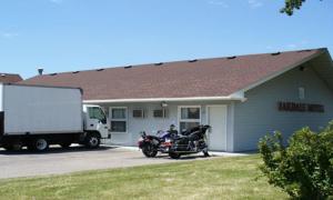una motocicleta estacionada frente a una casa con un camión en Oakdale Motel, en Owatonna