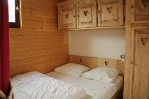 a bed in a wooden room with two pillows at Chaumière des Neiges CM1003 COSY & NATURE 4 Pers in Châtel