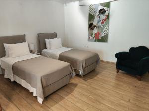 Habitación con 2 camas, una silla y una pintura en Ulysses Apartments Monastiraki, en Atenas