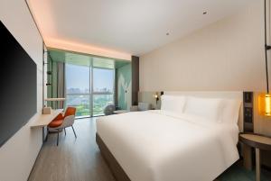 um quarto de hotel com uma cama grande e uma secretária em EVEN Hotel Qingdao Laoshan - an IHG Hotel em Qingdao